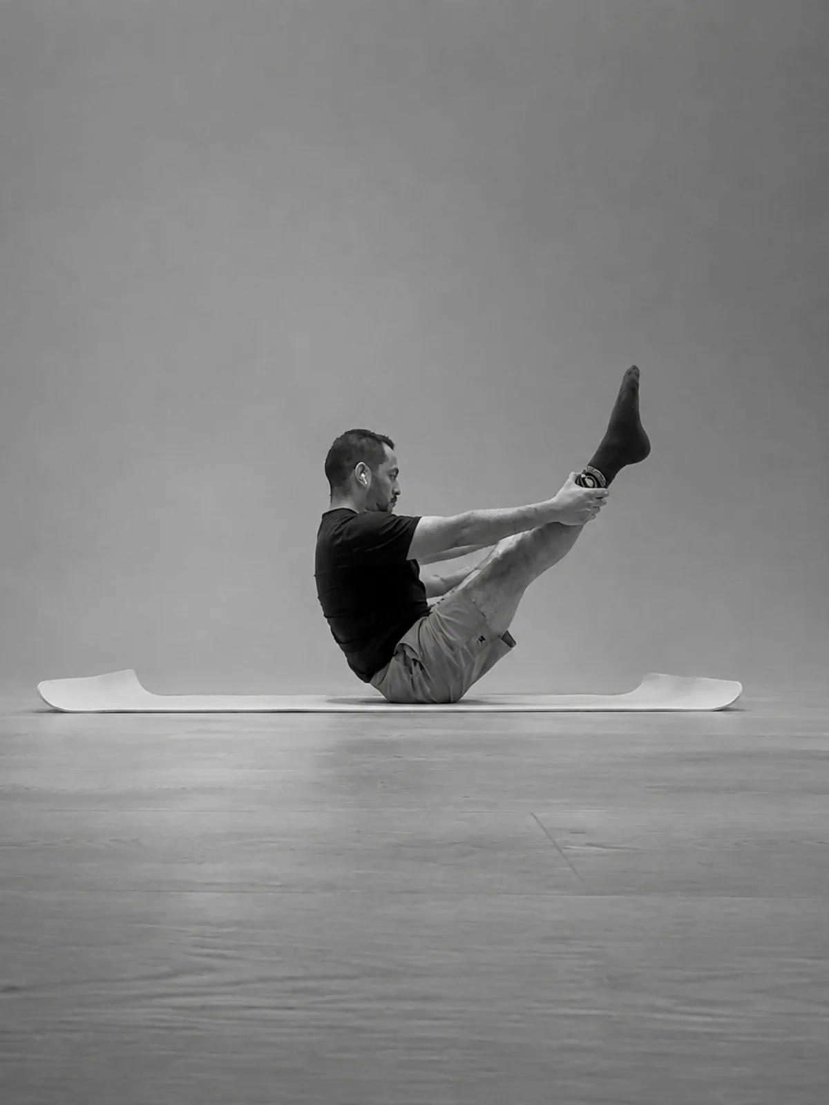 Joseal Pantoja practicando equilibrio sentado en Pilates Mat con las piernas elevadas.